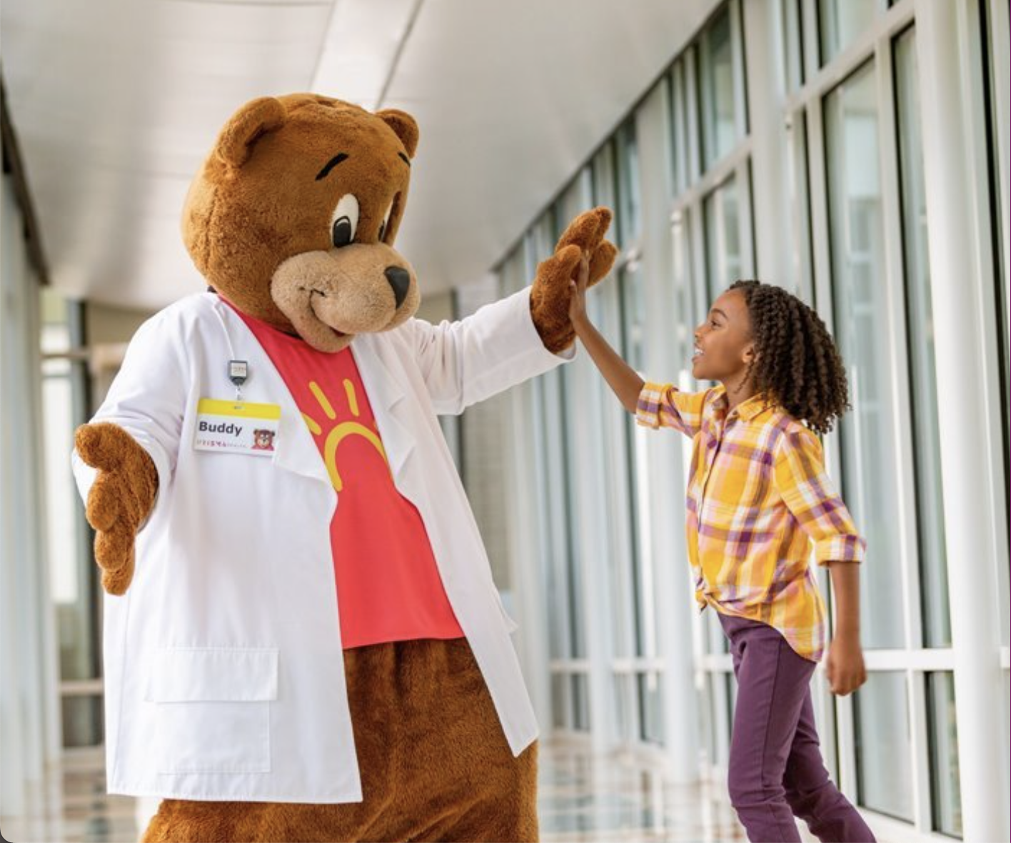 Child high-fiving Buddy the bear (costume)
