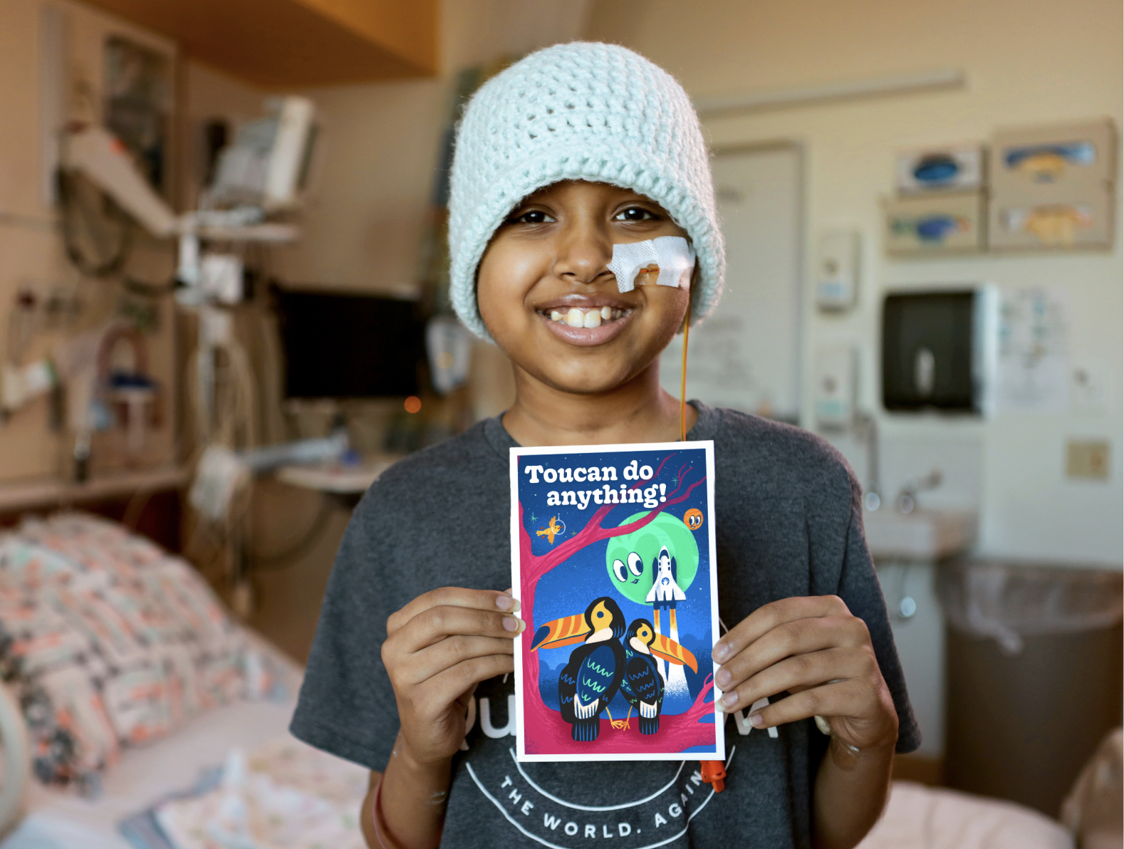 A child is smiling and holding a card that reads, "Toucan do anything!"