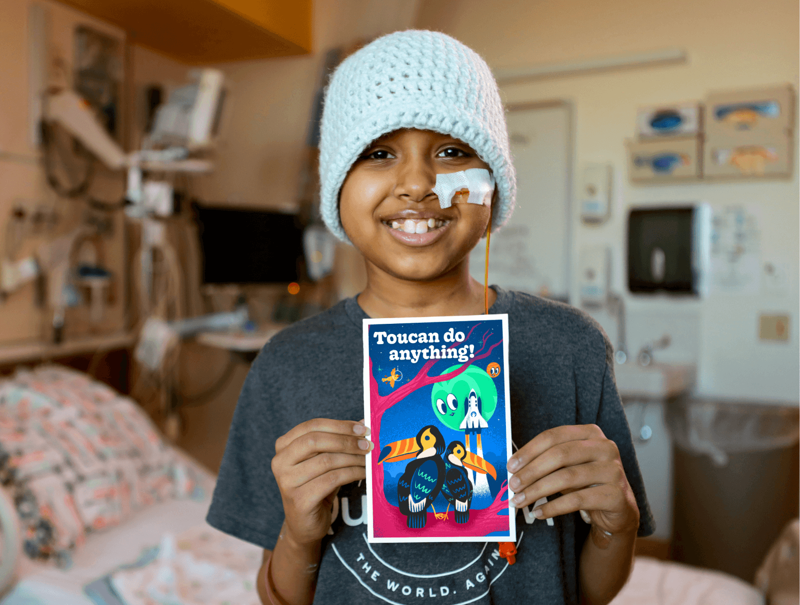 A child is smiling and holding a card that reads, "Toucan do anything!"