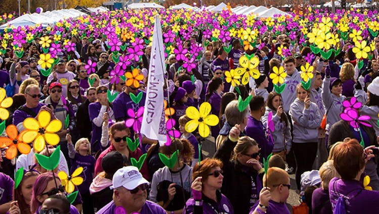 Large Crowd Of People Holding ALZ Flowers Wearing Matching Purple Sweatshirts 